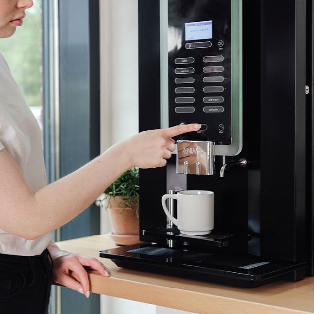 kvinde benytter sig af kaffemaskine