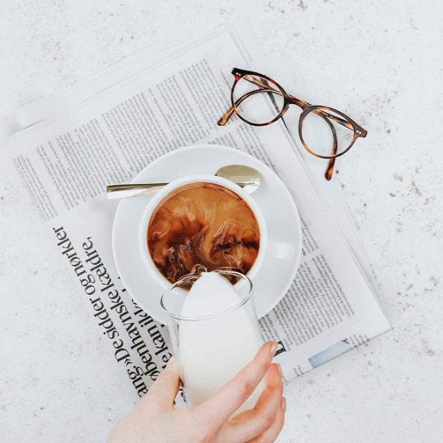 Mælk bliver hældt i bæredygtig kaffe på avis