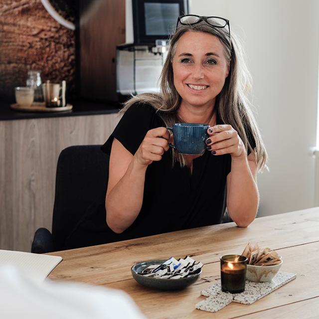 glad kvinde drikker af kaffeordning på arbejdspladsen 