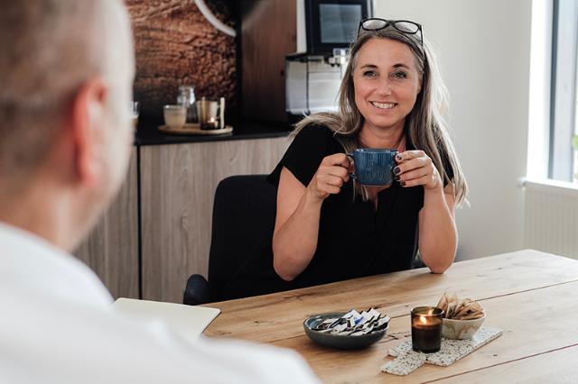 Kvinde drikker kaffe fra automatisk kaffemaskine på formalet kaffe
