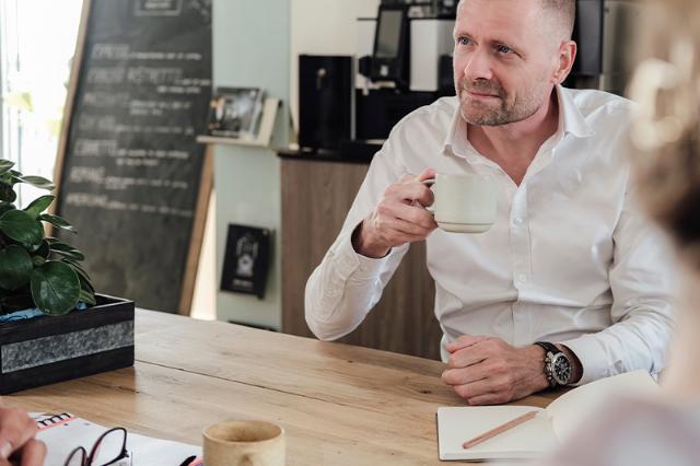 Mand drikker kaffe fra helbønne kaffeautomat